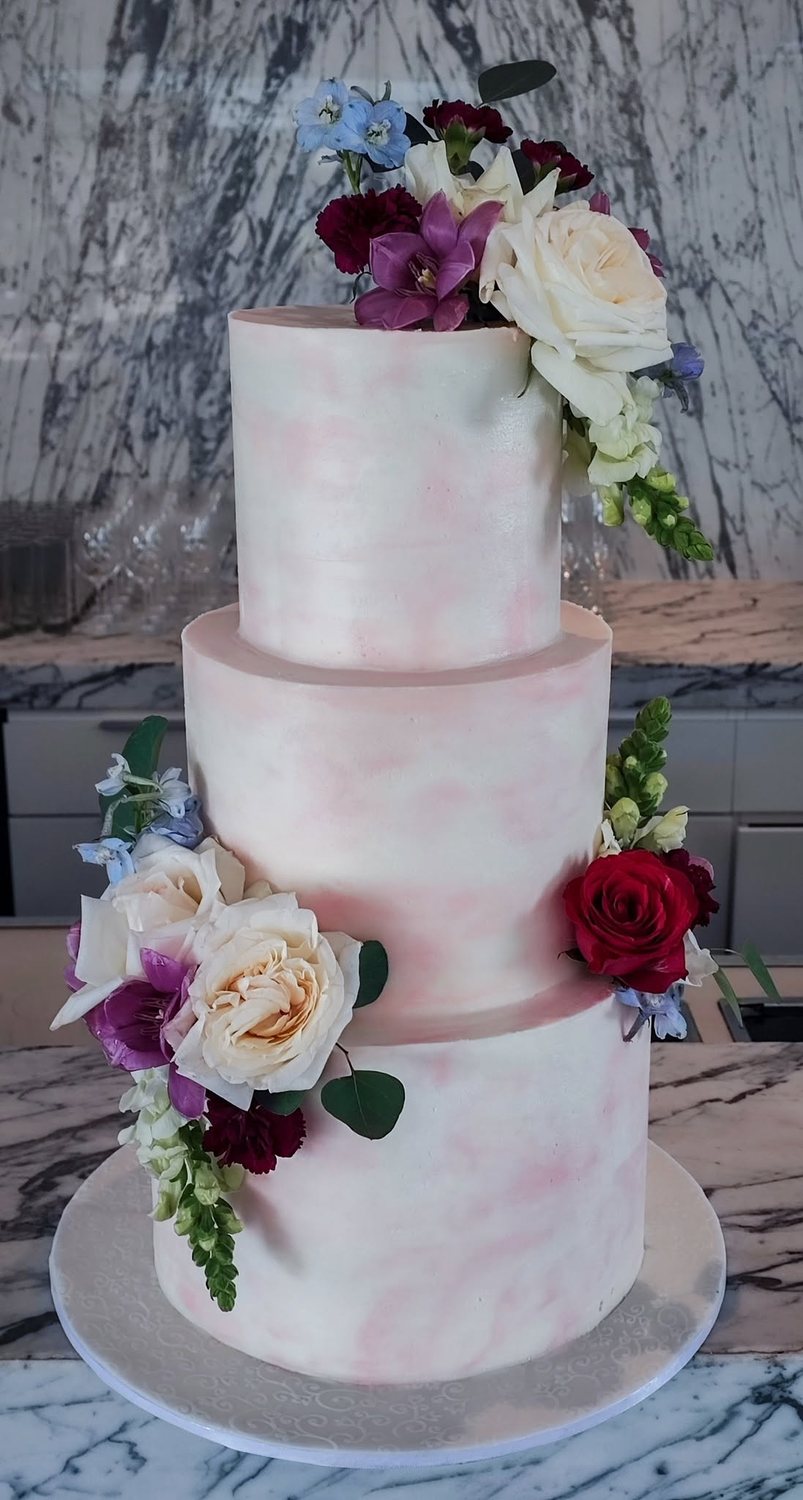 Tall pink wedding cake with floral decorations